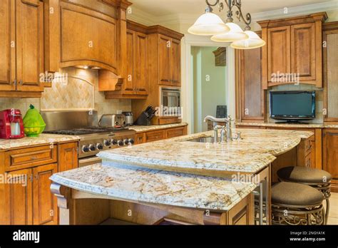 Wooden Cabinets And Island With Tan Nuanced Quartz Countertop Padded