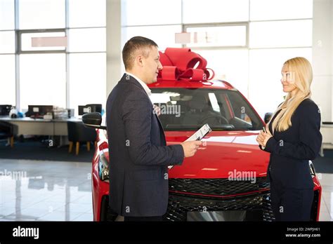 Dealer Communicates With A Blonde Customer In A Car Dealership Stock Photo Alamy