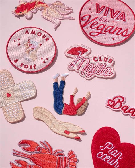 Various Embroidered Patches And Magnets On A Pink Surface With The