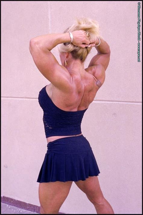 A Female Bodybuilt Posing For The Camera With Her Hands Behind Her Head