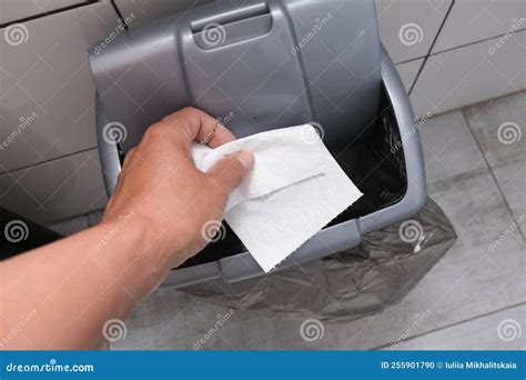 Human Hand Holding And Throwing Away A Tissue Toilet Paper To A Bin In