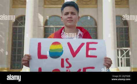 Gay Girl Showing Love Is Love Sign Wrapped In Lgbt Rainbow Flag At Pride Parade Stock Video