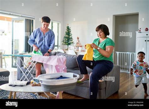 Lesbian Couple Folding Laundry And Ironing Clothes In Living Room Stock Photo Alamy