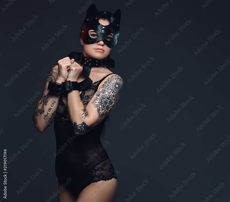 Sexy Woman Wearing Black Lingerie In BDSM Cat Leather Mask And Accessories Posing On Dark