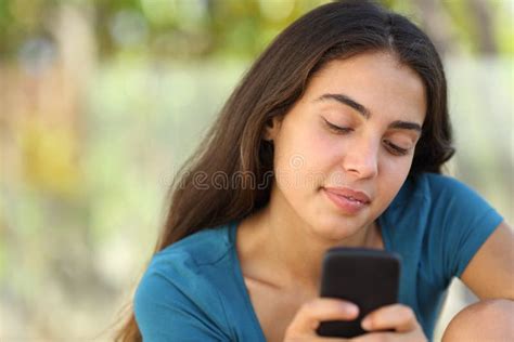 Menina Feliz Bonita Do Adolescente Que Texting Em Um Telefone Esperto