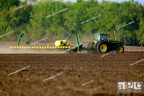 Agriculture A John Deere Tractor And Row Planter Planting Corn In