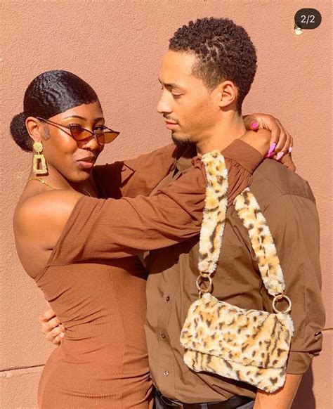 A Man And Woman Standing Next To Each Other In Front Of A Pink Wall