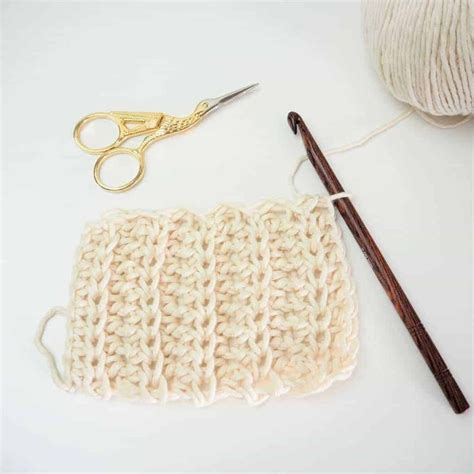 A Crochet Bag Next To A Pair Of Scissors And Yarn