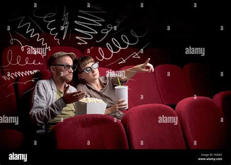 Young Cute Couple Sitting In Cinema And Eating Popcorn While Watching