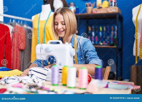 Young Blonde Woman Tailor Smiling Confident Using Sewing Machine At