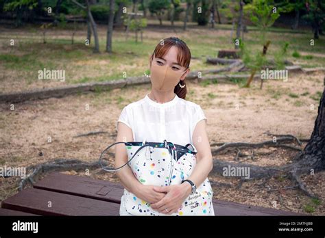 A Mature Japanese Woman Outdoors In A Park Wearing A Face Mask