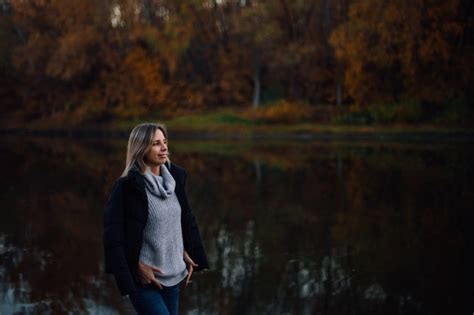 Charmante Femme Blonde Debout Au Bord De La Rivière En Détournant Les Yeux En Souriant Avec Une