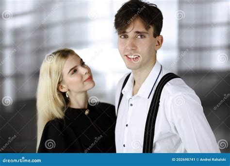 Young Couple Of Businessman And Woman Are Standing In A Modern Office