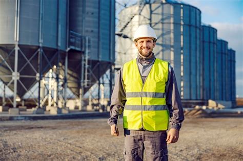 Retrato de un trabajador de fábrica parado frente a silos llenos de