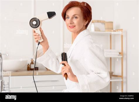 Mature Redhead Woman With Brush Drying Hair In Bathroom Stock Photo Alamy