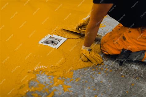 Профессиональный строитель, наносящий краску для пола или новый слой ...