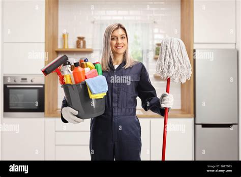 Young Female Cleaner In A Uniform Holding A Bucket Of Cleaning Supplies