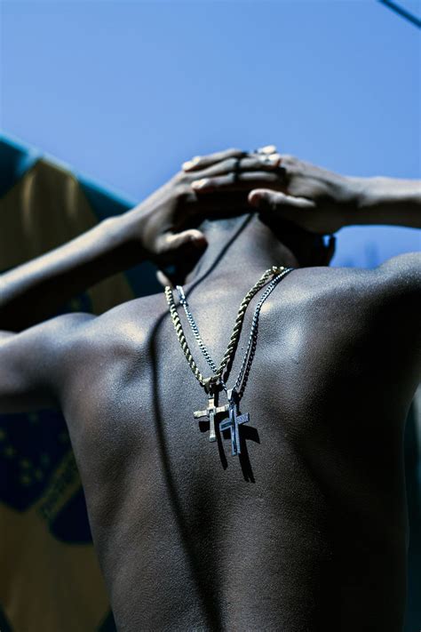 A Man With His Back Turned To The Camera Wearing A Cross Necklace