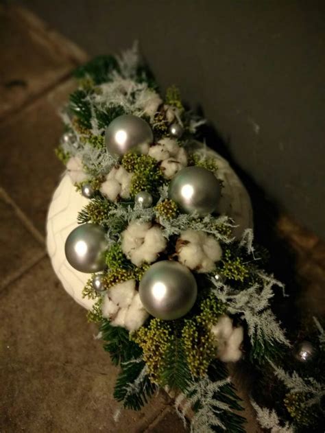 A White Cake Decorated With Silver Ornaments And Greenery