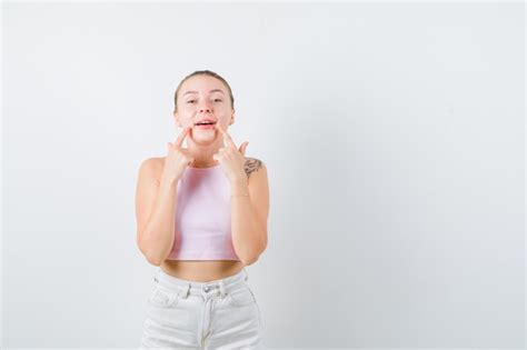 La Fille Blonde Fait Le Sourire Avec Ses Doigts Sur Le Fond Blanc Photo Gratuite