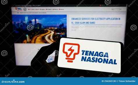 Person Holding Mobile Phone With Logo Of Malaysian Company Tenaga