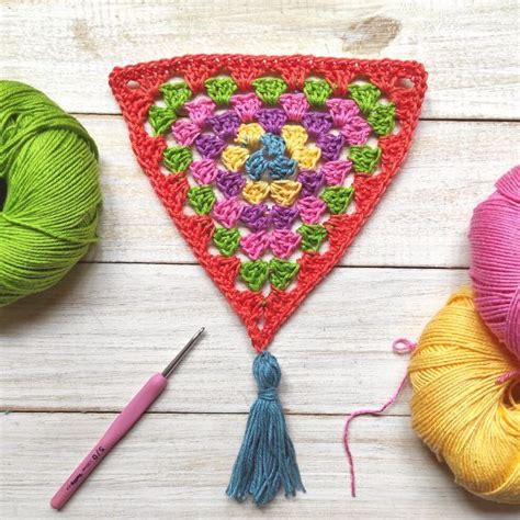 A Crocheted Triangle Is Next To Two Balls Of Yarn