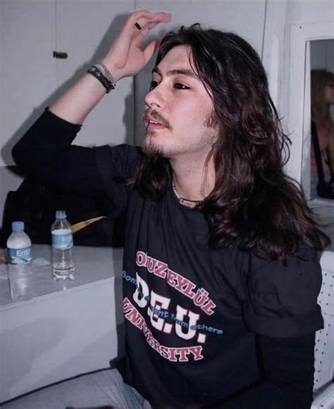 A Man With Long Hair Sitting In Front Of A Mirror Holding His Hand Up