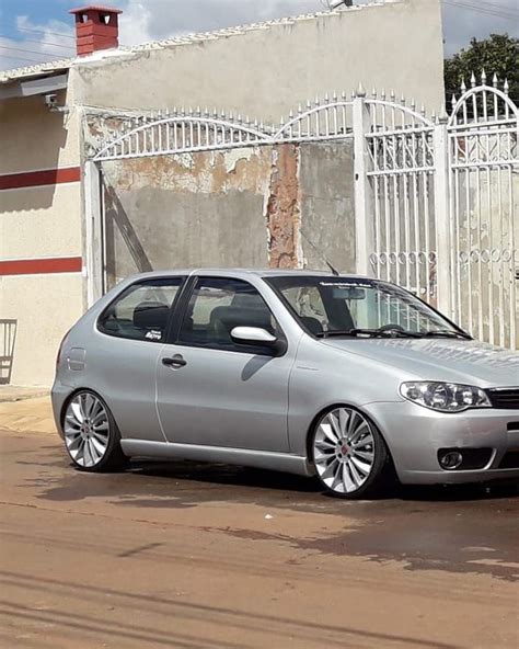 A Silver Car Parked In Front Of A White Fence