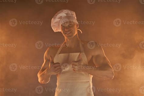 Portrait Of Muscular Chef Wearing White Apron And Chef Hat Showing