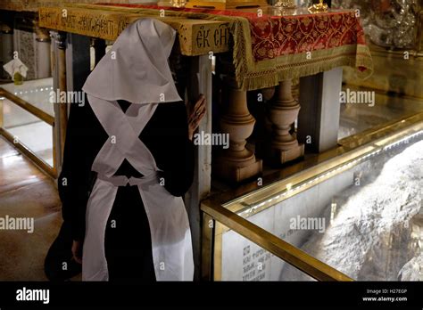 An Eastern Orthodox Nun Kneel Before The Altar Of The Crucifixion On