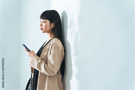 壁にもたれかかってスマホを見るおしゃれな女性 Stock 写真 | Adobe Stock