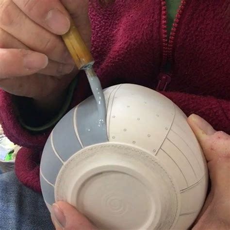 A Person Is Pouring Something Into A White Bowl With A Straw In Its Mouth