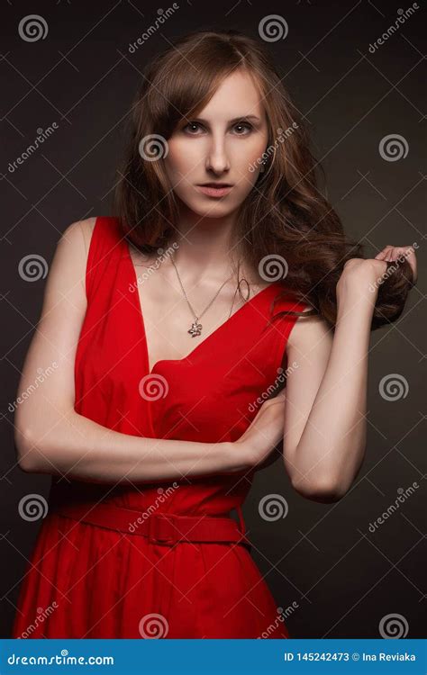Authentic Brunette Model Girl With Nude Makeup And With Trendy Hairstyle In A Red Short Dress
