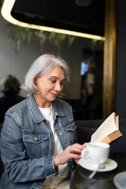 Mulher idosa lendo um livro e tomando café em um café Foto Premium