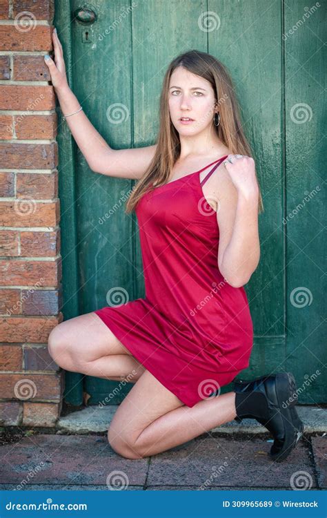 Brunette Girl In A Red Dress Kneeling In Front Of A Green Door Stock Image Image Of Elegant