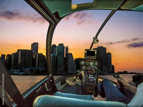 Helicopter cockpit on New York skyline at sunset, with pilot arm and ...