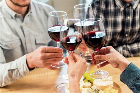 Close Up View Of Friends Clinking Glasses Of Wine While Eating Cheese