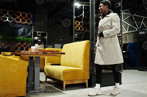 Handsome african american man posing inside night club in black hat and