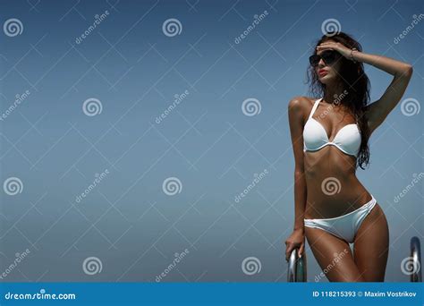 Elegant Woman In The White Bikini On The Sun Tanned Slim Body Is Posing