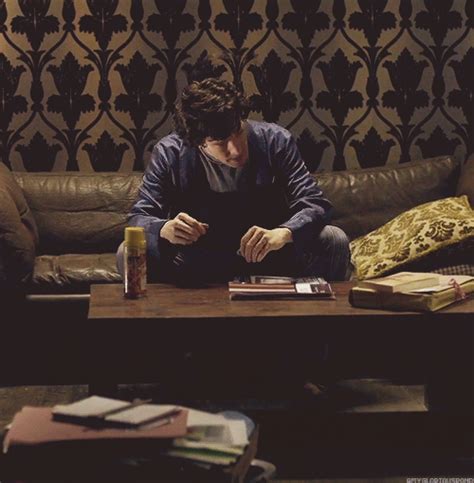 A Man Sitting On Top Of A Couch Next To A Table With Books And Drinks