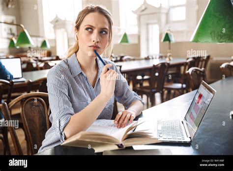 Attractive Blonde Girl Student Studying At The Library With Laptop Computer Stock Photo Alamy