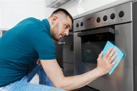 Premium Photo Man With Rag Cleaning Oven Door At Home Kitchen