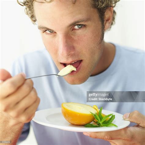 Closeup Of A Young Man Eating Orange Sorbet With A Spoon High Res Stock