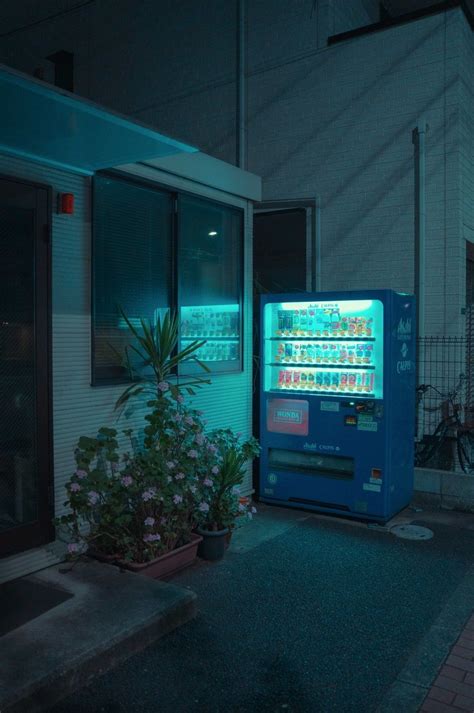 A Vending Machine Sitting In Front Of A Building With Flowers Growing