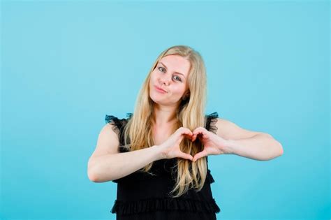 La Fille Blonde Heureuse Montre Le Geste De Coeur Avec Des Mains Sur Le Fond Bleu Photo Gratuite