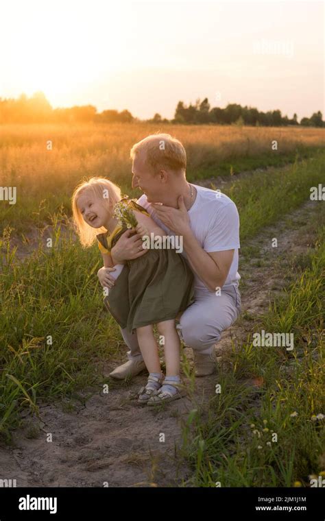 Papa und seine blonde Tochter gehen und haben Spaß auf einem Kamillenfeld Das Konzept von