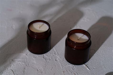 Vela aromática en un frasco de vidrio sobre un fondo blanco con sombras