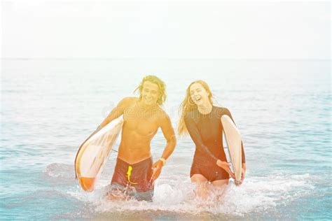 Surfers At The Beach Smiling Couple Of Surfers Walking On The Beach