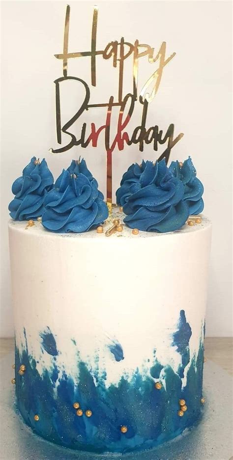 A Birthday Cake With Blue Frosting And Gold Sprinkles That Says Happy