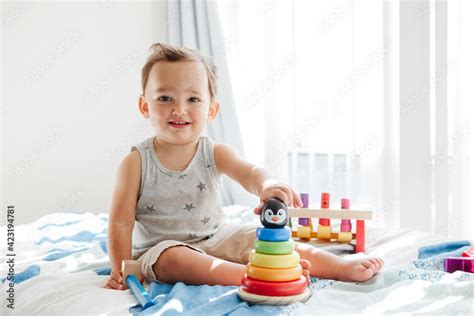 Cute baby toddler playing with learning toy pyramid stacking blocks at ...